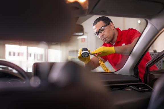 Autotechnicus met veiligheidsbril repareert voorruit met gereedschap, met focus op Carglass-expertise.